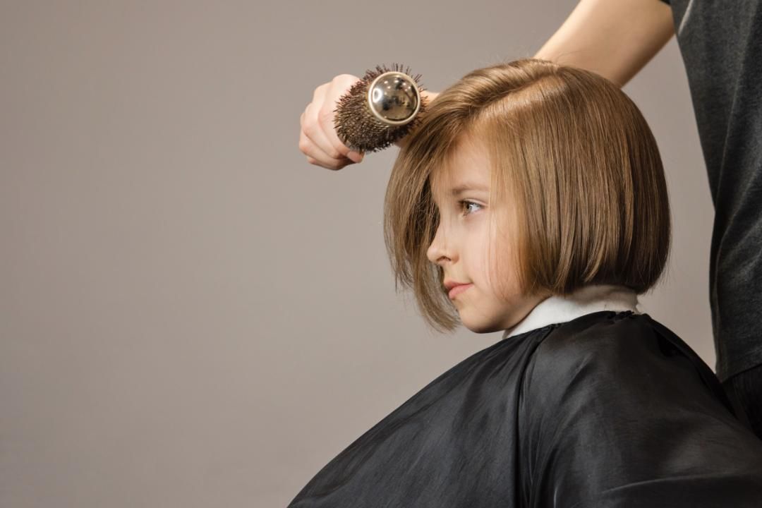 Manos de peluquero peinando a una niña