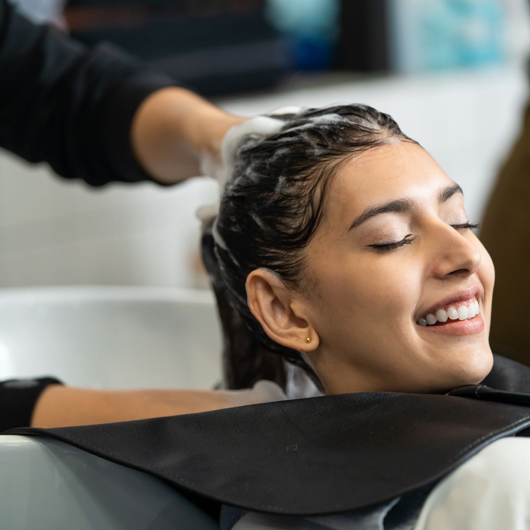 mujer sonriendo mientras le lavan la cabeza